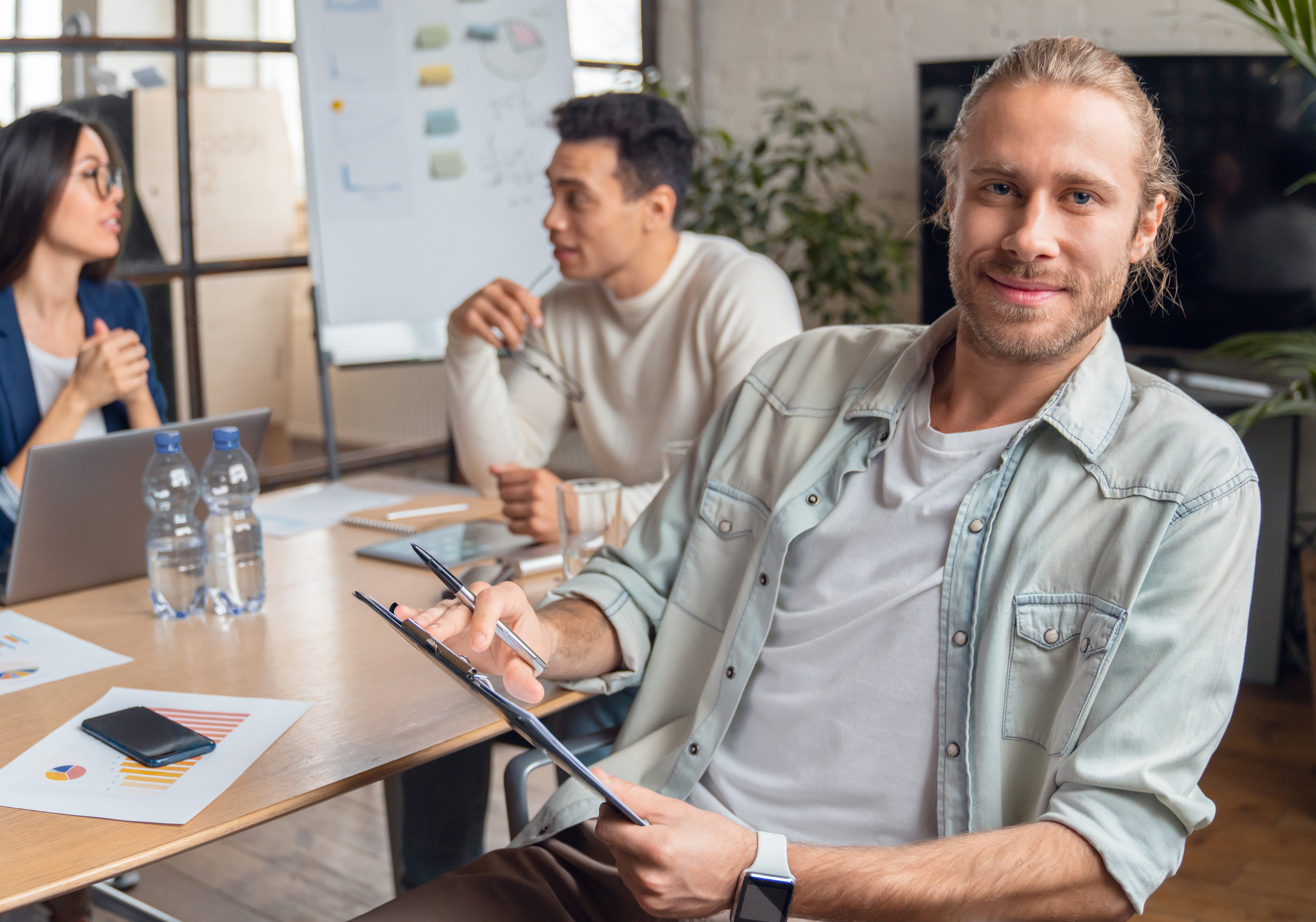 Young man sitting in office and looking at camera. Smiling businessman in casual clothes sitting