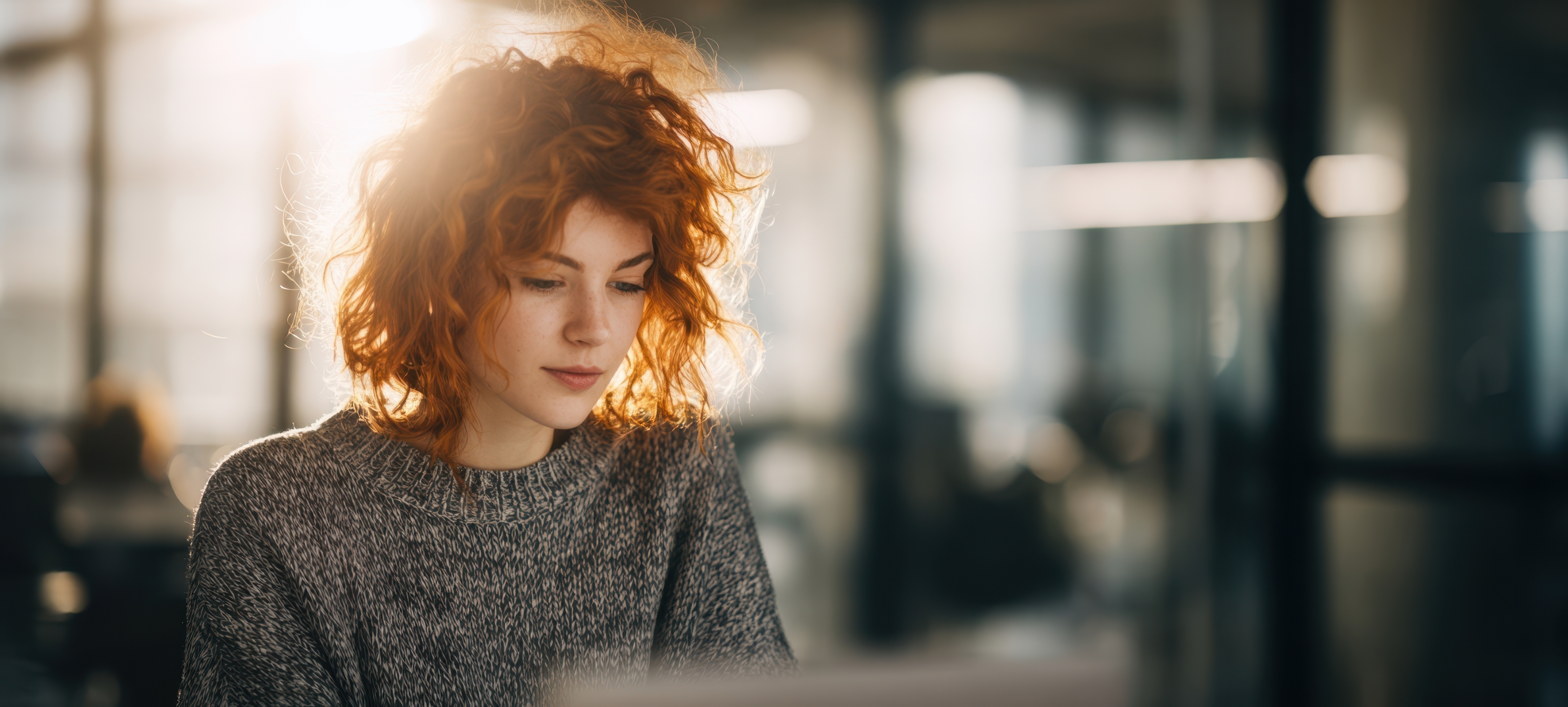 The beautiful young woman focused on her laptop in a modern workspace.