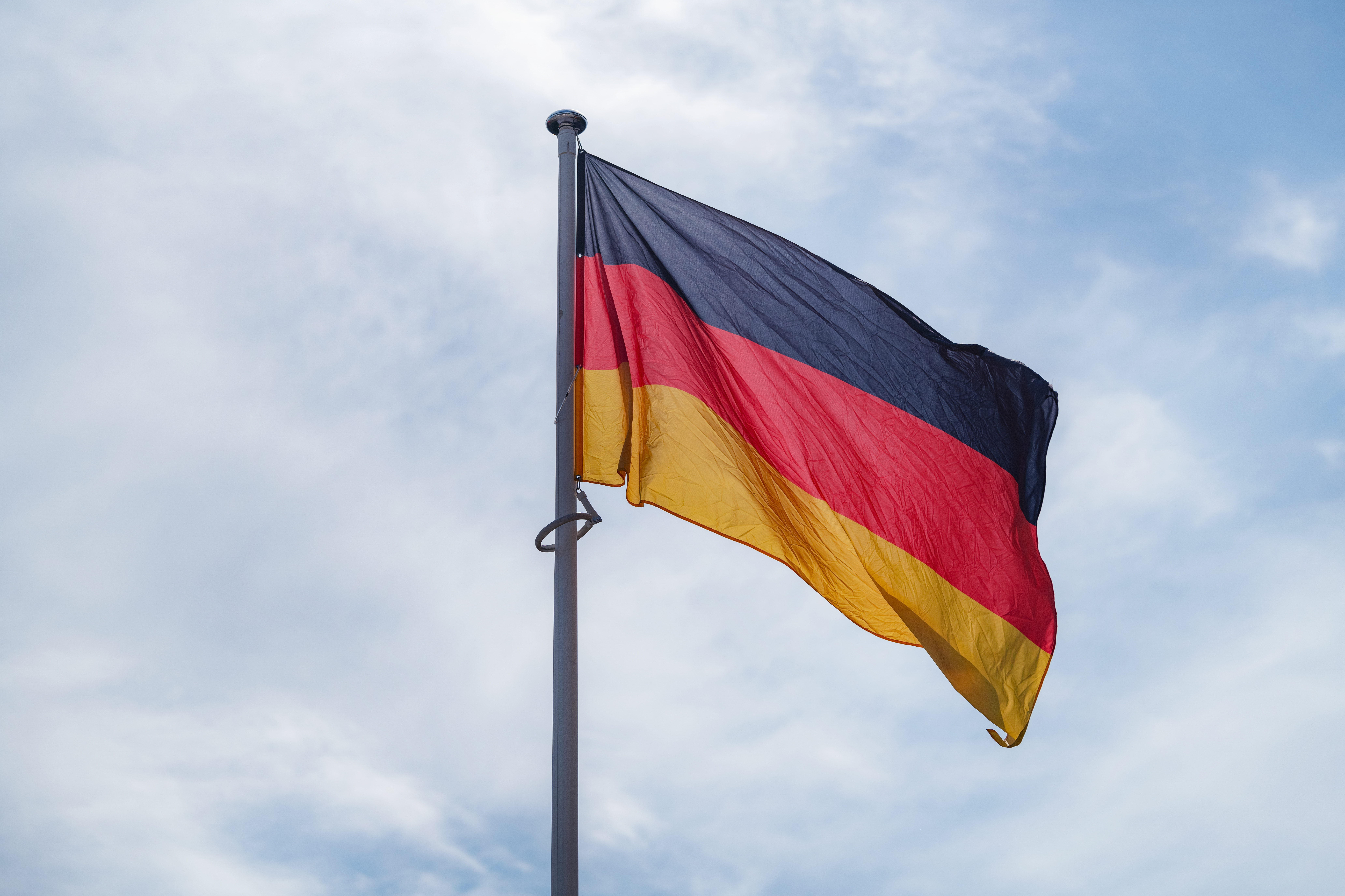 The national flag of Germany waving in the blue sky