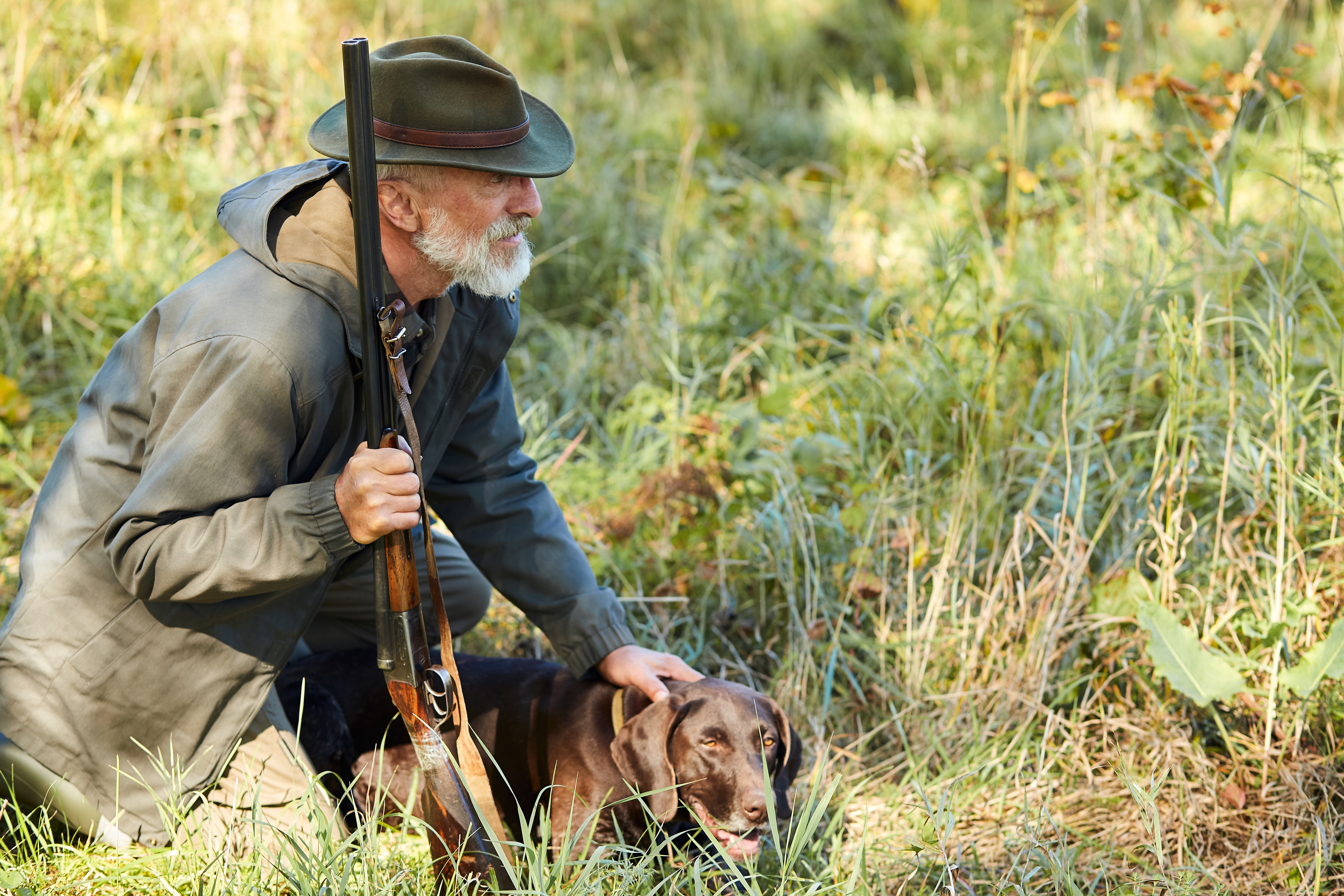 Hunter and his dog looking for trophy in forest